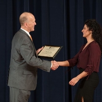 Doctor Potteiger shaking hands with an award recipient in a chocolate colored shirt